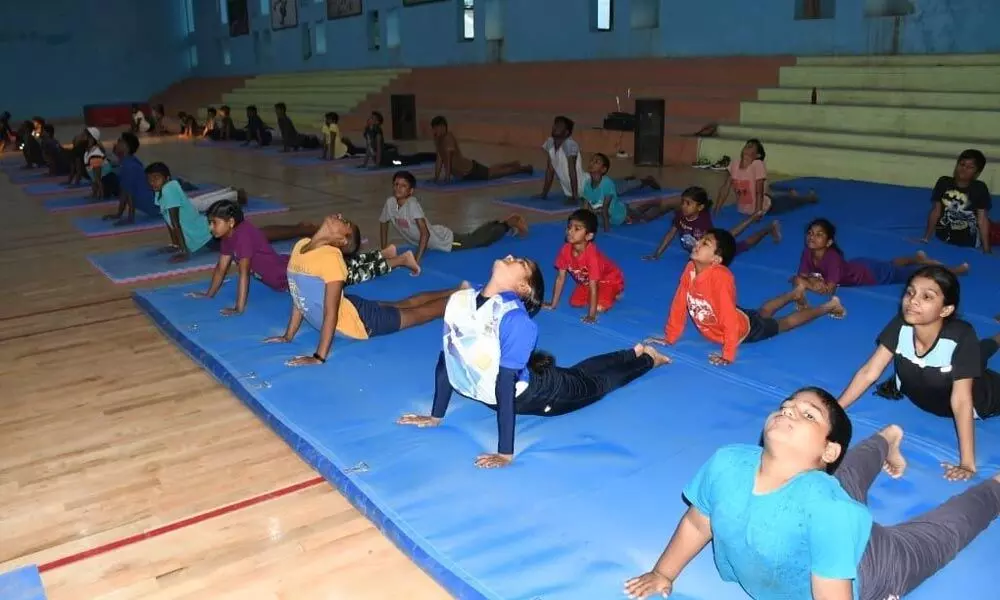 Students participating in mass Suryanamaskaram programme at the outdoor stadium in Kurnool on Tuesday