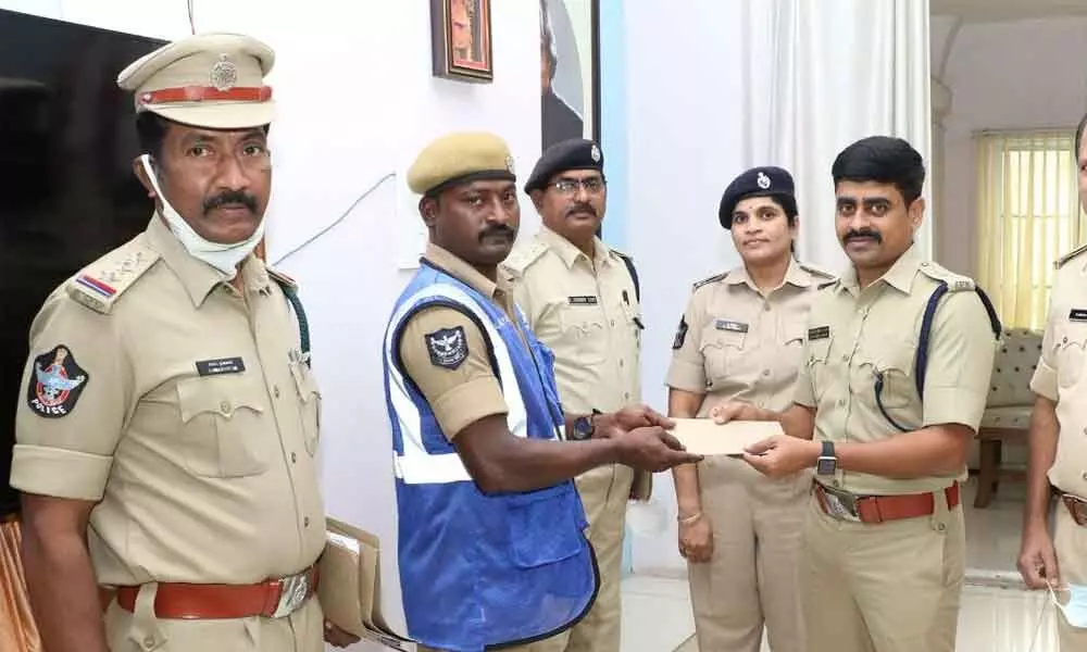 SP Venkata Appala Naidu handing over reward to Home Guard Siva Kumar at his chamber in DPO in Tirupati on Monday.