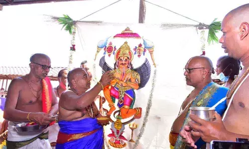 Priests of Yadadri temple hoisting the flag with picture of Lord Vishnu vehicle Garuda on Dhwaja Stambha of Balalayam under Dwajarohanam programme on Saturday