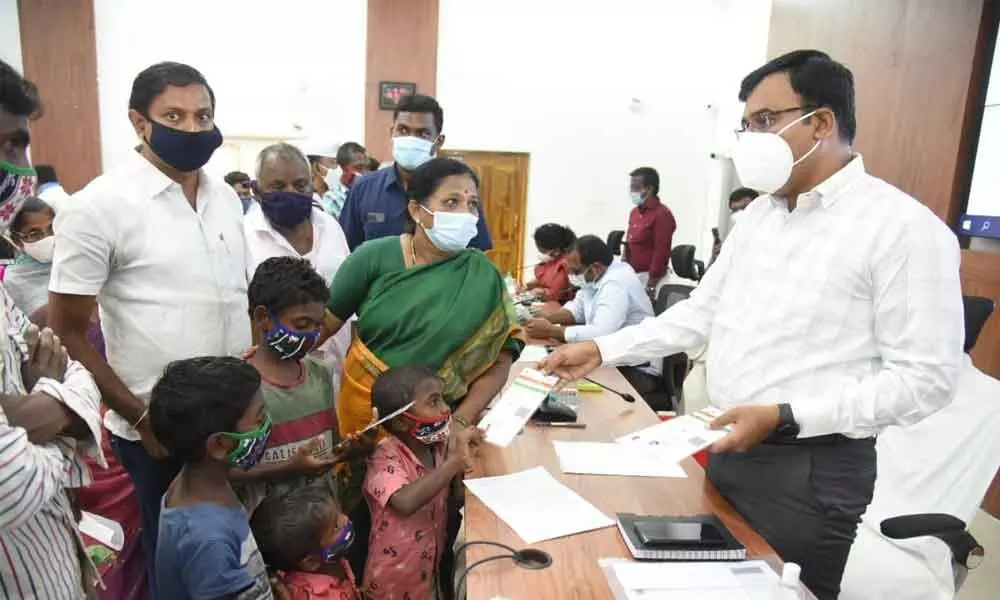 District Collector KVN Chakradhar Babu handing over Aadhaar card to a tribal family at the Collectorate in Nellore on Monday
