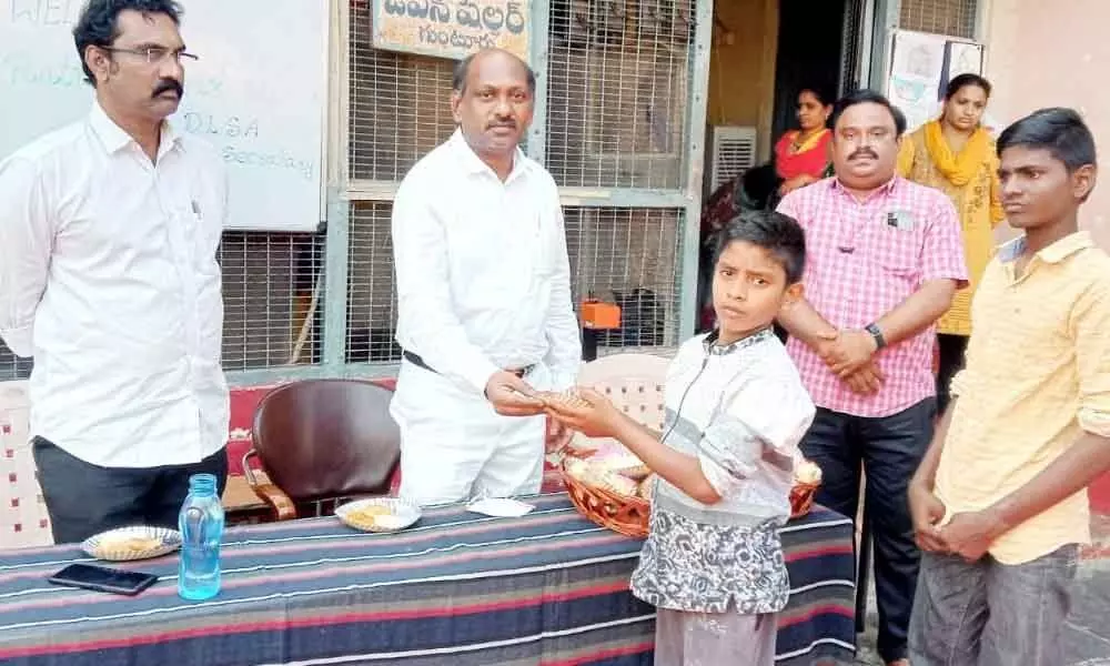 DLSA secretary K Ratna Kumar distributing snacks to the children at Open Shelter Home in Guntur on Monday