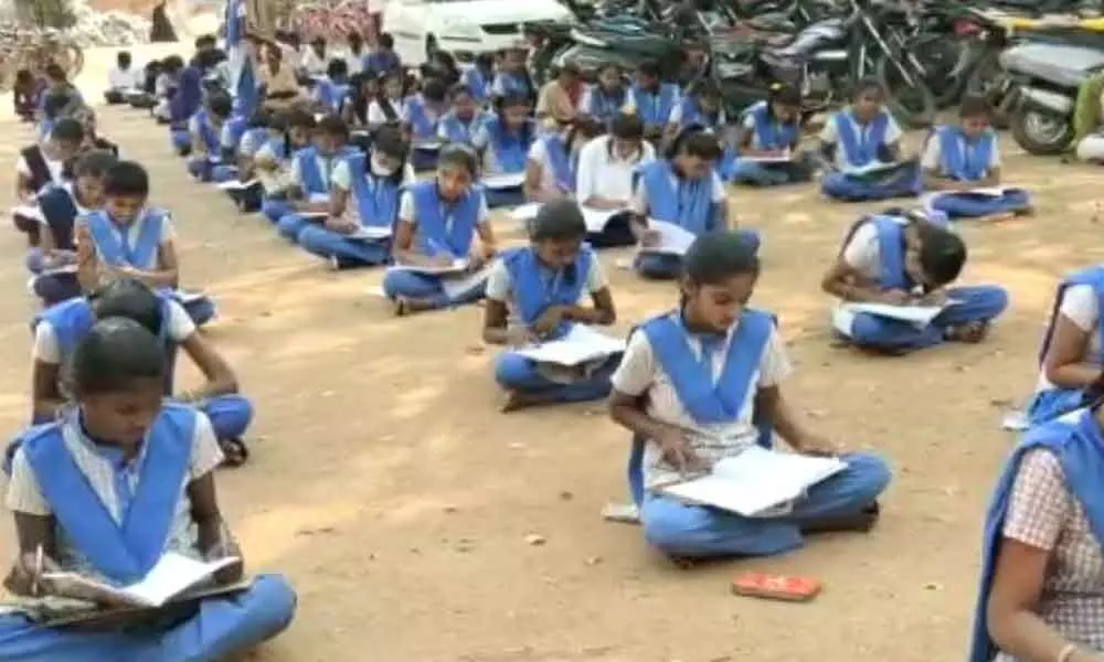 Students sit on bare ground to take lessons in school