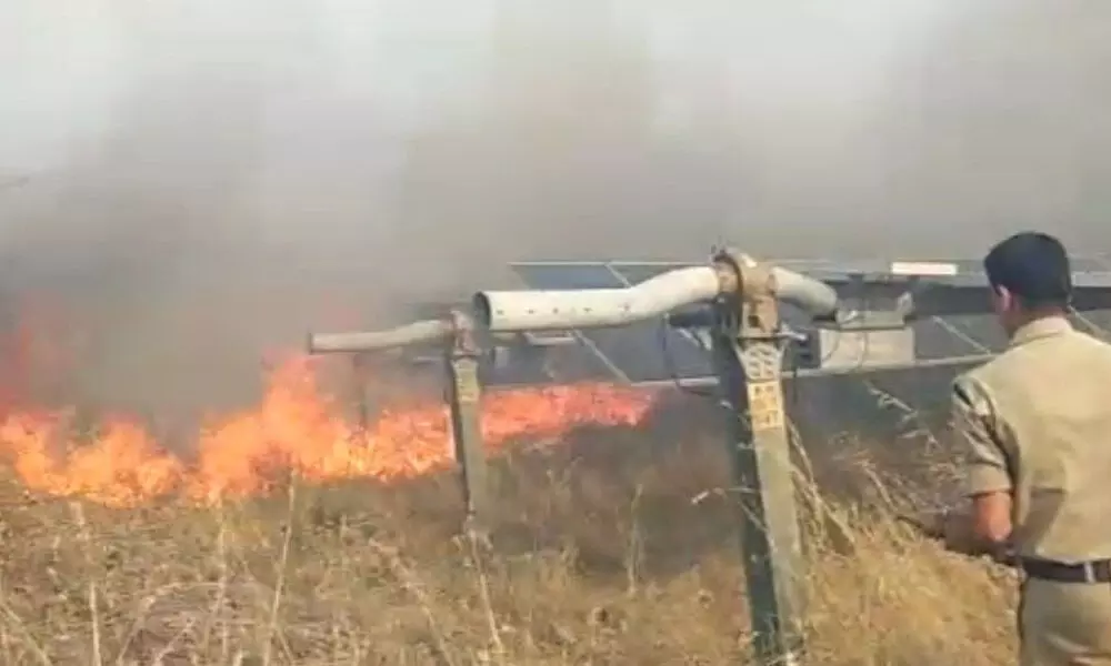 A Fire department official dousing fire to save the solar power plant in Achampet on Monday