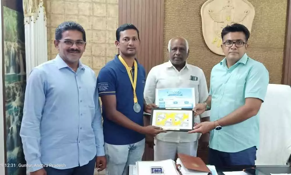 Guntur Range DIG CM Trivikrama Varma giving a memento to the NTR Municipal Corporation Stadium swimming head coach Sk Khaza Mohiddin who bagged first prize in 4-KM sea swimming held in Goa recently