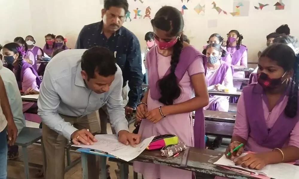 Konaseema district collector Himanshu Kaushik checking a student’s book in ZP school at Bodasakurru on Wednesday
