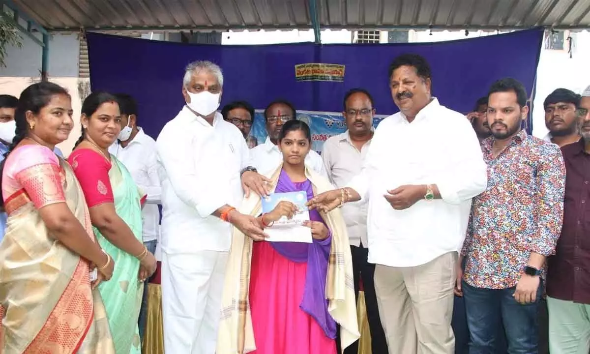 Civil Supplies Minister Karumuri Venkata Nageswara Rao and  MLA Malladi Vishnu present an award to a ward volunteer in Vijayawada on Wednesday