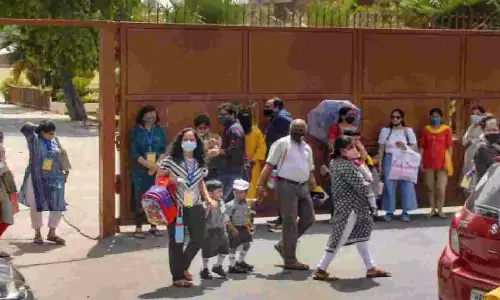 Students leave with their parents after attending the Delhi Public School, in Noida on Wednesday. The school has shifted the class of a student who tested positive to online mode