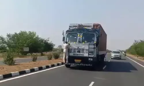 A toll plaza employee cling to the lorry bumper for scaning fast tag  at Amukathadu toll plaza in Dhone mandal of Nandyal on Wednesday
