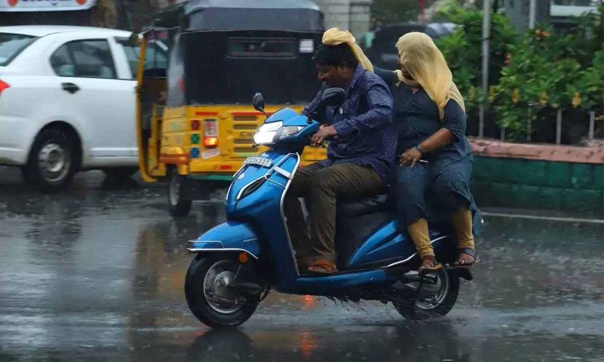 A couple going on bike caught off guard by rainsin Tirupati on Wednesday