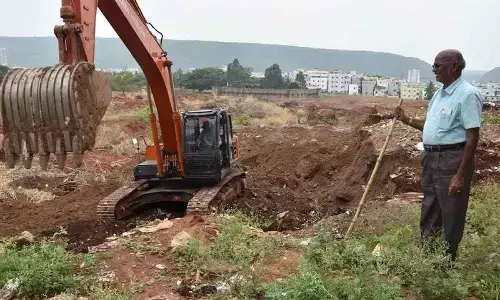 A site filled with weeds and bushes being cleared at Andhra University Engineering College in Visakhapatnam