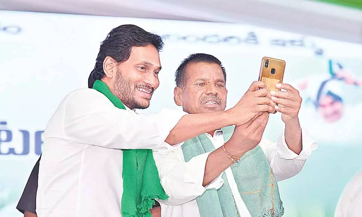 A farmer takes a selfie with Chief Minister Y S Jagan Mohan Reddy during YSR Free Crop Insurance programme at Chenne Kothapalli village in Sri Sathya Sai district on Tuesday