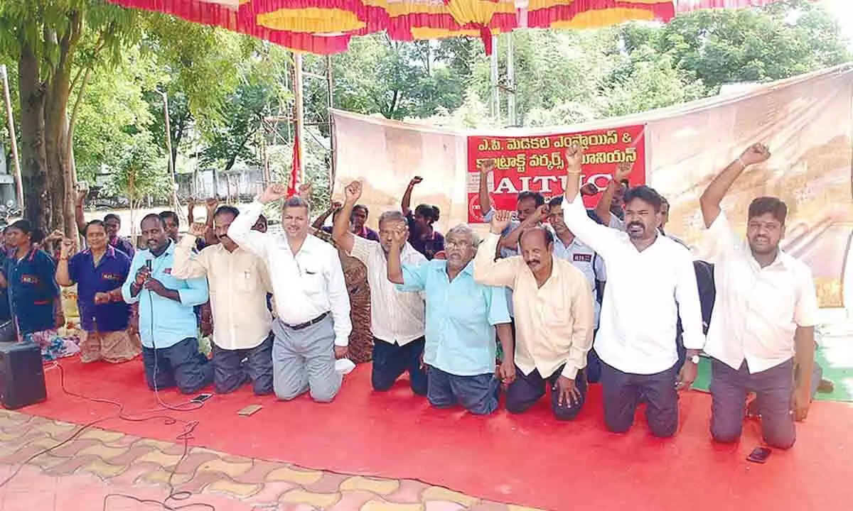 ESI contract employees demanding their pending salaries by standing on knees in front of the hospital in Tirupati on Sunday.