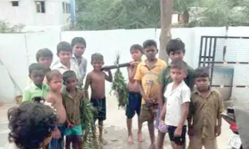 Children carrying a frog tied to pestle decorated with neem leaves at Agasanuru village in Kosigi mandal on Monday