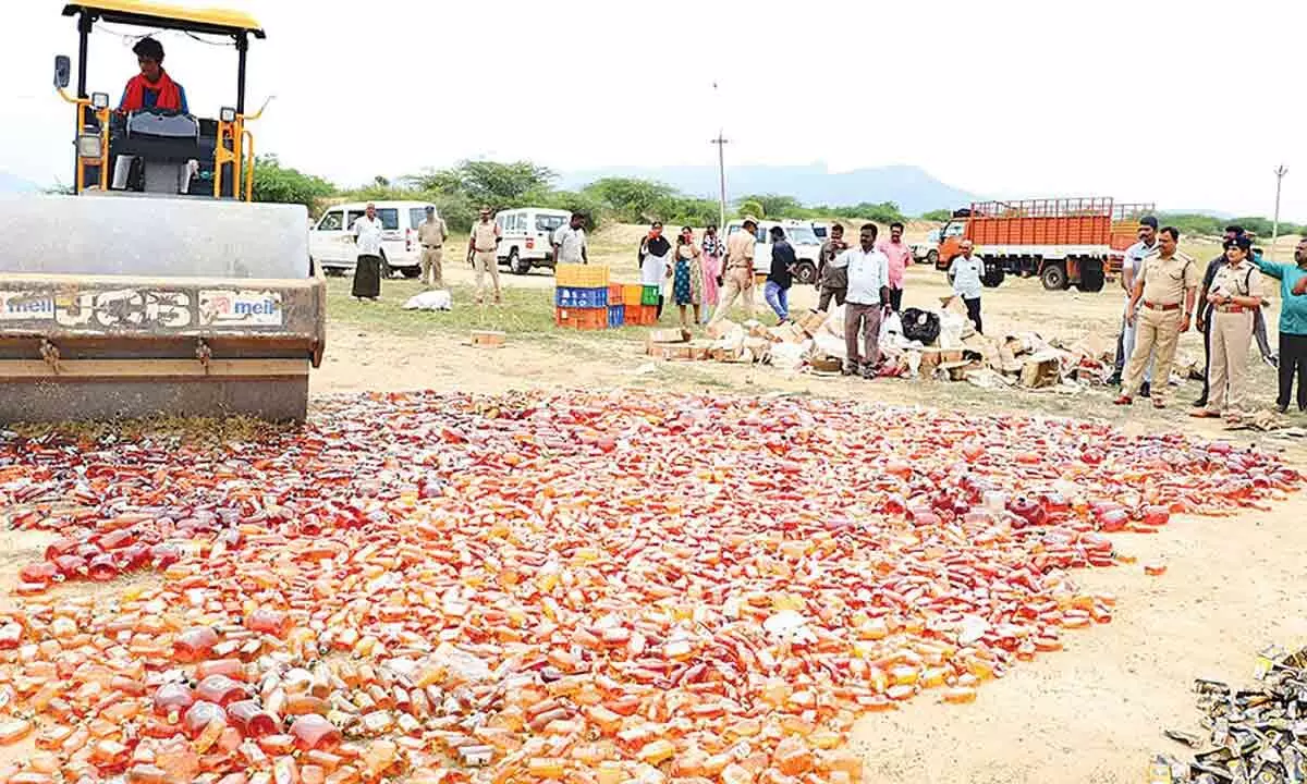 Police officials destroying seized liquor bottles at Chinna Cheruvu in Renigunta mandal on Tuesday