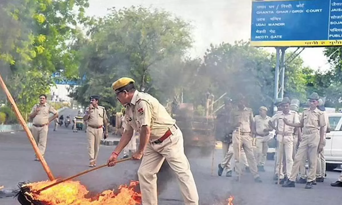 Police try to douse tyres burnt during a protest against killing of Kanhaiya Lal in Udaipur, in Jodhpur. (Photo | PTI)