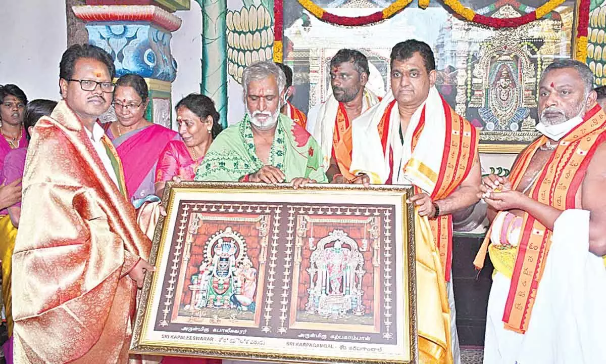 Temple Executive Officer S Lavanna presenting laminated photo of presiding deities to the Minister P Sekhar Babu in Srisailam on Sunday