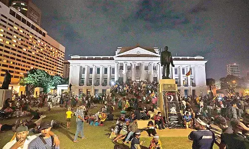 Protesters sit and walk around after storming into Sri Lankan presidents office, in Colombo on Saturday