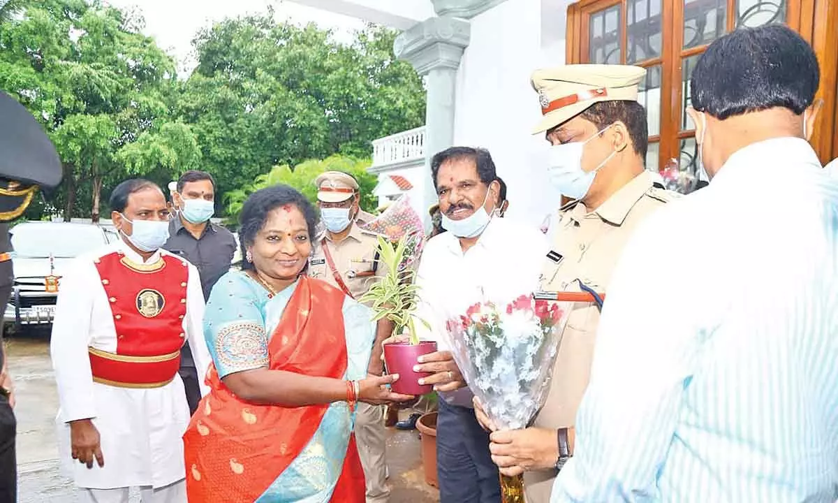 Additional Collector Vanmala Chandrashekar presenting a plant to Governor Tamilisai Soundrararajan at a guest house in Narketpally on Tuesday