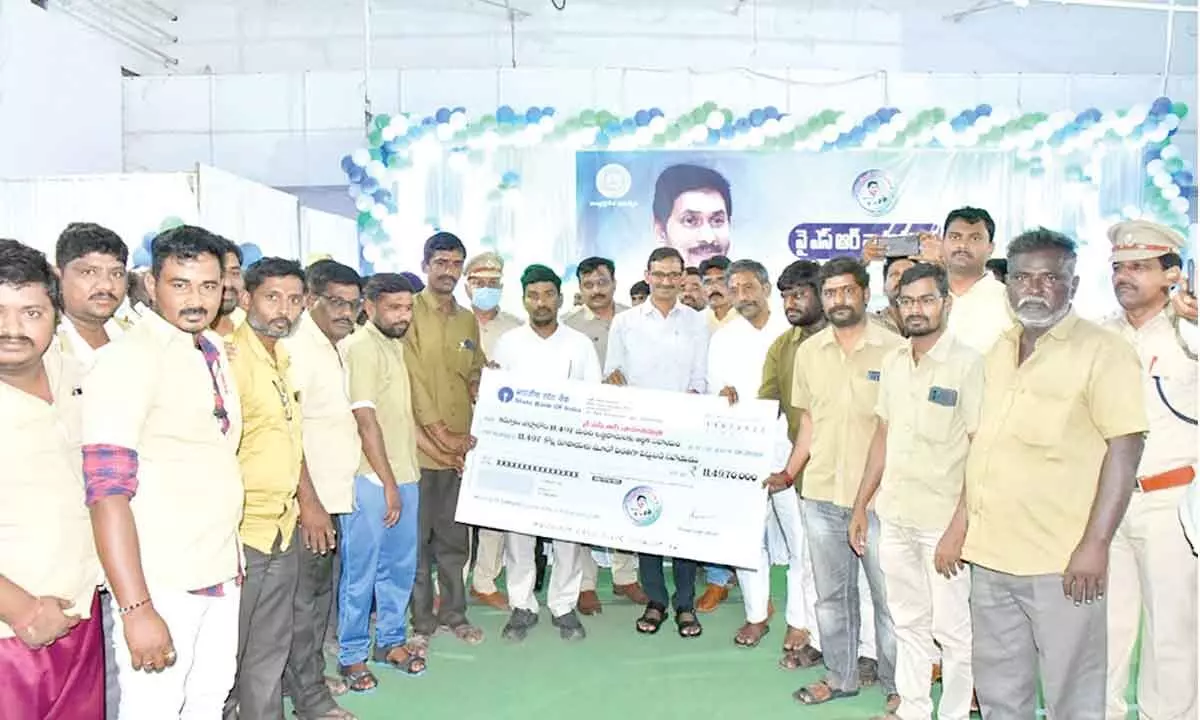 District Collector P Koteshwara Rao handing over the replica of YSR Vahana Mitra cheque to the auto drivers, in Kurnool on Friday