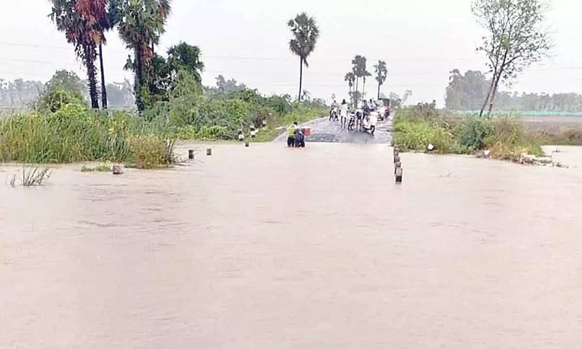 Floodwater overflowing on the road at Parasa village of Amaravati mandal in Palnadu district on Friday