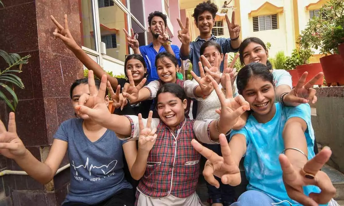 Students flash victory signs as they celebrate their success after the announcement of CBSE Class 12th exam results, at a school in Patna on Friday