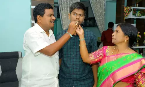 File photo of Polu Lakshmi Sai Lohith Reddy’s parents Polu Malyadri Reddy and Lakshmikantha offering a sweet to him, who secured second rank in AP EAPCET-2022 in Ongole