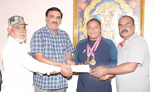 Veda Seeds Executive Director Tulasi Dharma Charan presenting a cheque for Rs 25,000 to power lifter Nagam Gnana Divya in Guntur on Tuesday