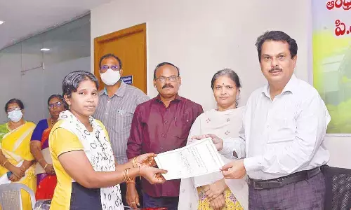 AP CRDA Additional Commissioner Aleem Basha distributing house allotment letter to a beneficiary in Tulluru on Thursday