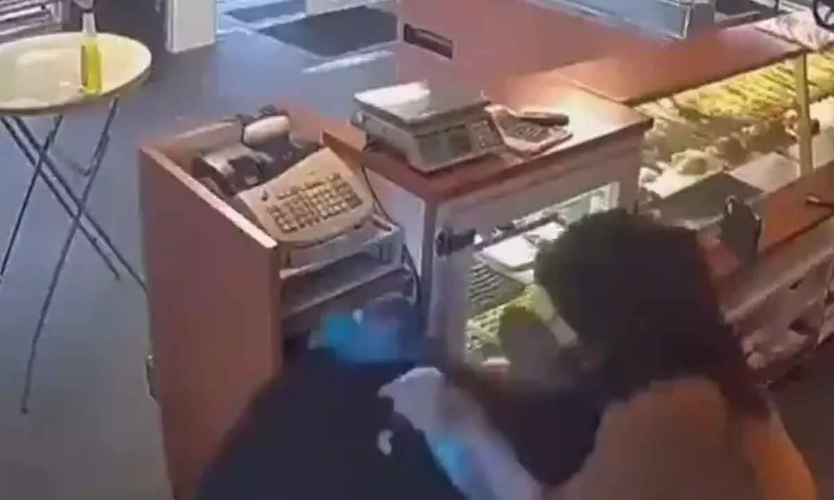 Picture shows woman striking robber with cleaning cloth and spray.