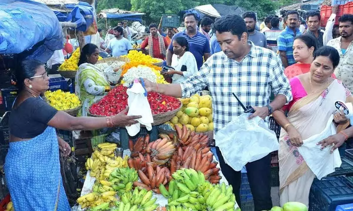 Municipal Commissioner G Lakshmisha giving away a cloth bag to a flower vendor in Visakhapatnam on Sunday