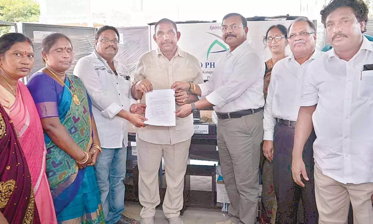 Pithapuram MLA Pendem Dorababu and Aurobindo Pharma Foundation (APF) senior officer CRM Naidu handing over the material check list to the Headmaster of ZP High School, Konapapapeta, on Wednesday