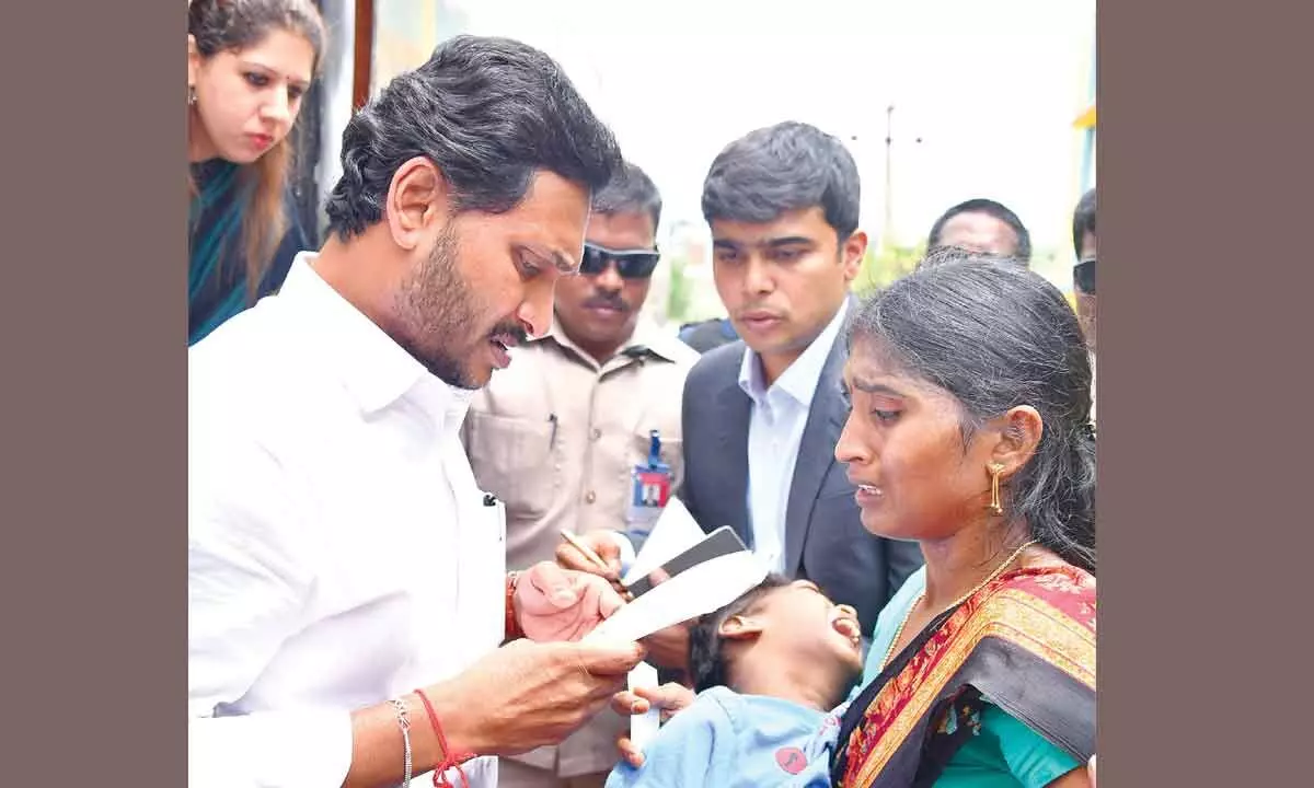 Chief Minister Y S Jagan Mohan Reddy listens to a mother, Tanuja, after stopping his convoy at Tuni in Kakinada district on Thursday