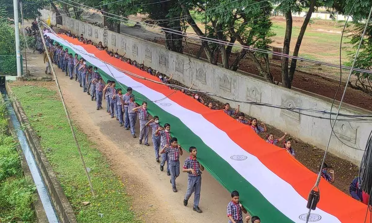Kendriya Vidyalaya students carrying a 75-meter-long national flag during a campaign in Kakinada on Friday