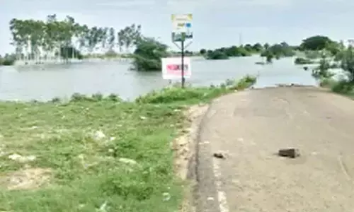 Floodwater overflowing on the bridge at Pedamaddur of Amaravati mandal on Friday