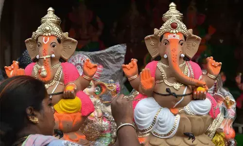 An artisan gives finishing touches to an idol of Lord Ganesha ahead of Ganesh Chaturthi  festival at Pottery Town in Bengaluru on Tuesday