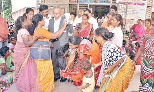 Women agitators touching the feet of DME Dr Satya Varaprasad at the maternity hospital in Tirupati on Friday.