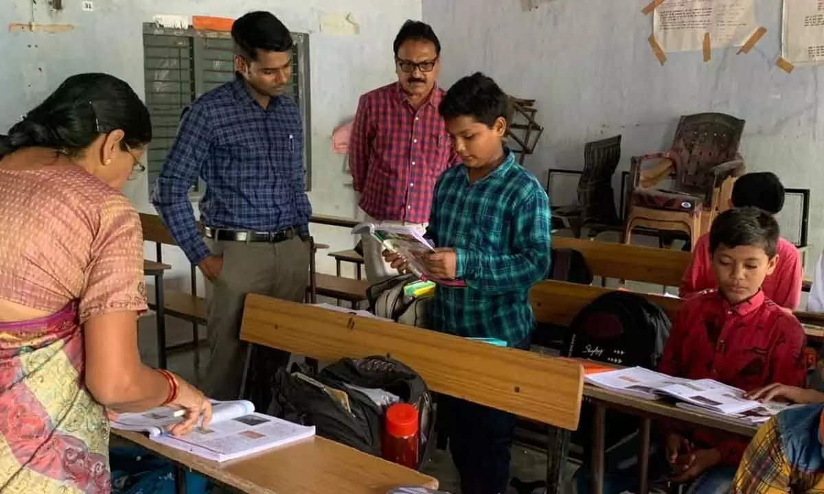 District Collector Anudeep Durishetty testing reading skills of students at a ZPHS school at Jagannadapuram village in Kothagudem district  on Tuesday