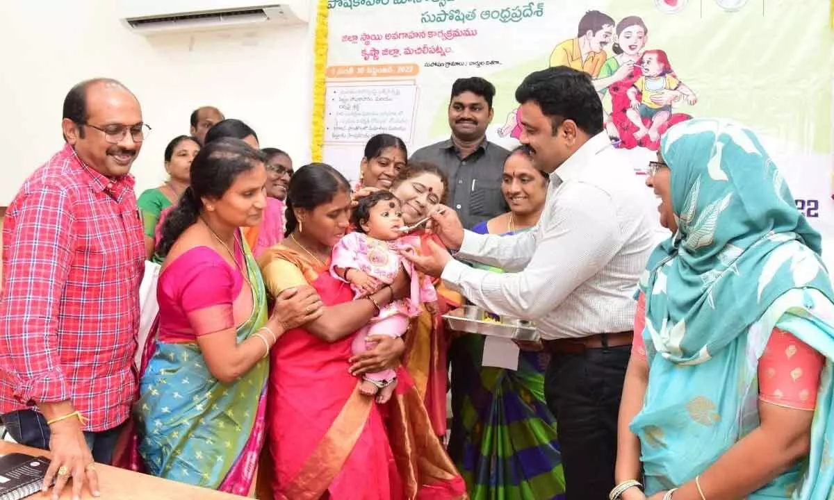District Collector P Ranjith Basha feeding the children at a programme at the Collectorate in Machilipatnam on Tuesday