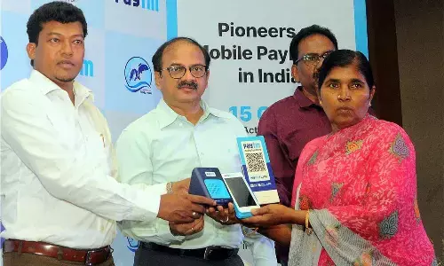 Minister for Animal Husbandry Dr Seediri Appalaraju distributing Point of Sale (PoS) payment device and speaker to a beneficiary at a programme in Vijayawada on Tuesday  Photo: Ch Venkata Mastan