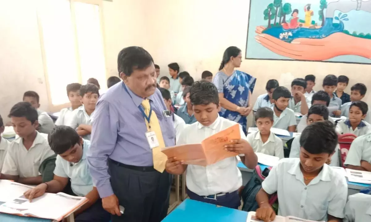 CAV Prasad, member of State School Education, Control and Monitoring Committee, examining the reading ability of a student at Srinivasa Ramanujan Corporation High School in Rajamahendravaram on Thursday