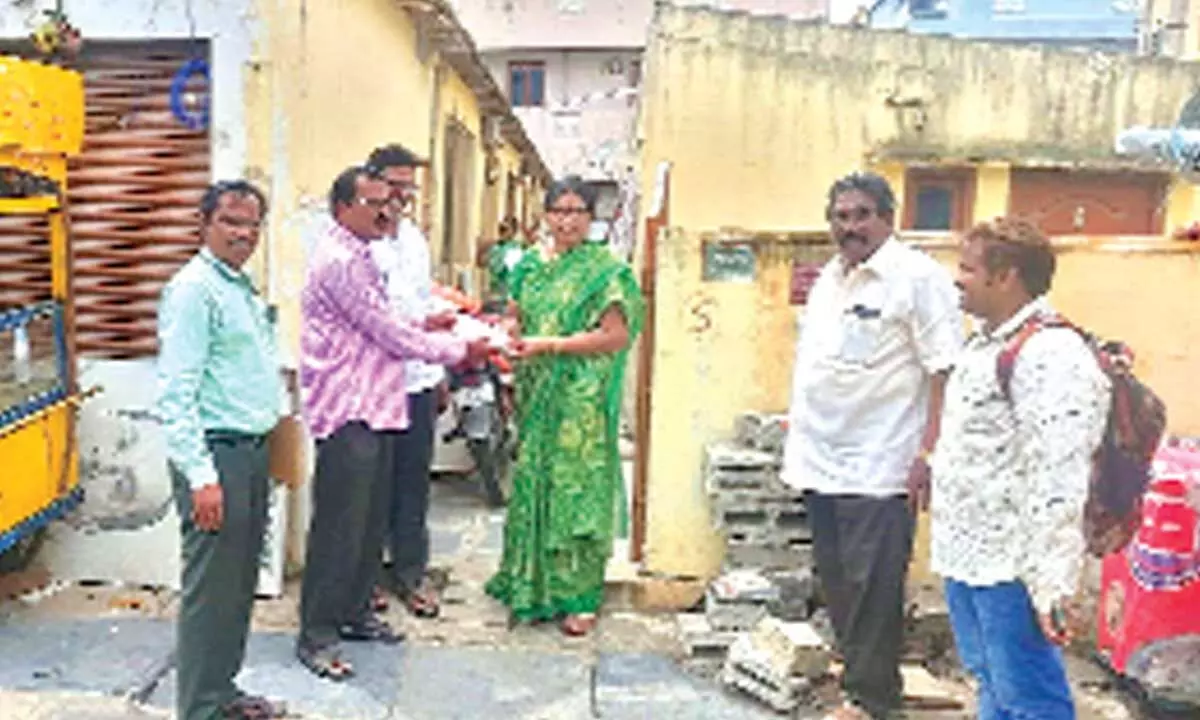 GMC officials handing over compensation cheque to a house owner at AT Agraharam in Guntur on Tuesday