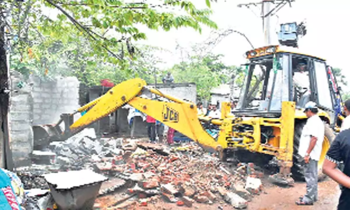 KMC authorities removing house sheds with the help of a JCB at Ayodhya Nagar in Kakinaga on Thursday
