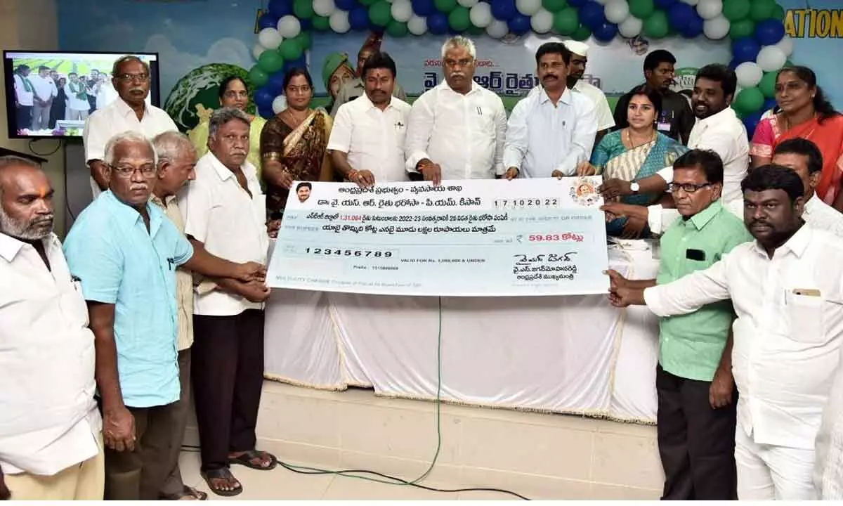MLAs Malladi Vishnu and Velampalli Srinivasa Rao, and NTR District Collector S Dilli Rao presenting specimen cheque to farmers in Vijayawada on Monday