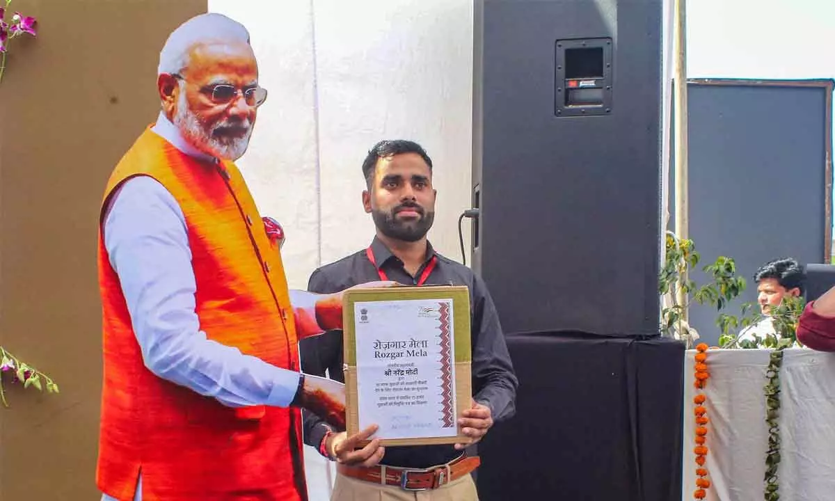 A qualified candidate poses for photo with a cutout of Prime Minister Narendra Modi after receiving his appointment letter during the launch ceremony of Rozgar Mela, a recruitment drive for 10 lakh personnel, in Bhopal on Saturday