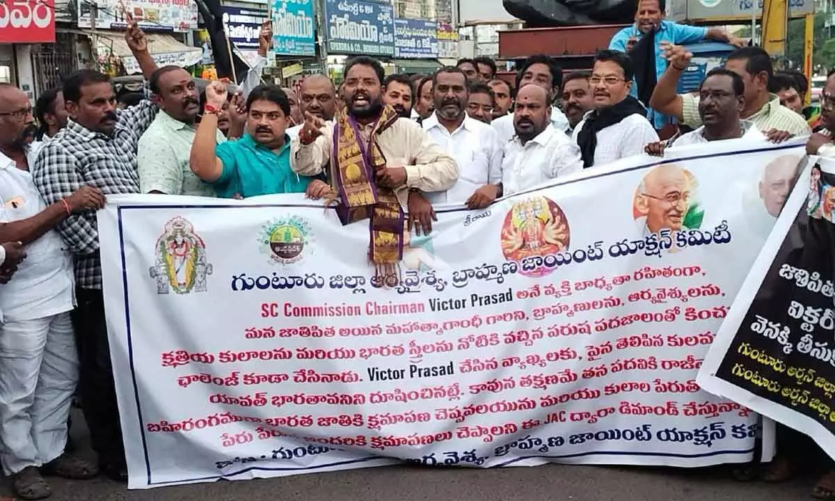 MLA Maddali Giridhara Rao and leaders of Arya Vysya Sangam and AP Brahmana Chaitanya Vedika staging a protest at Mahatma Gandhi statue in Guntur on Friday