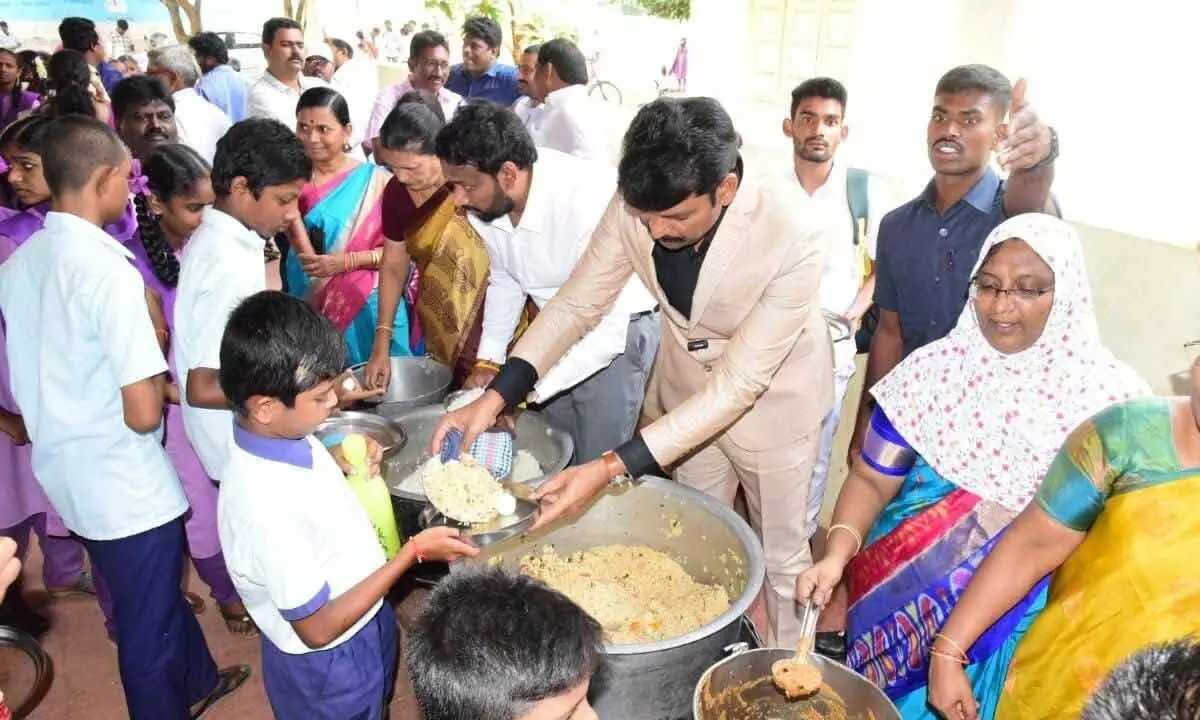 AP Food Commission chairman Ch Vijay Pratap Reddy serving food to students during his visit to Vuyyur village of Krishna district on Thursday