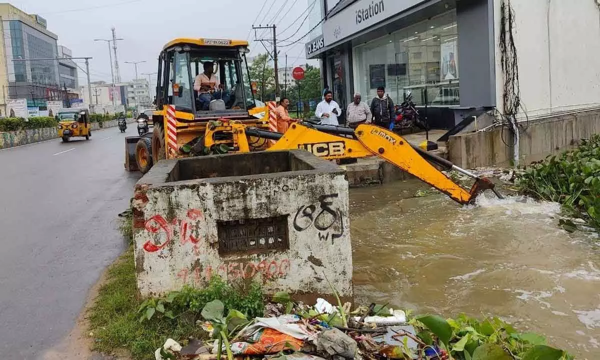 A canal being cleared by a JCB machine for free flow of water in Nellore rural limits on Monday