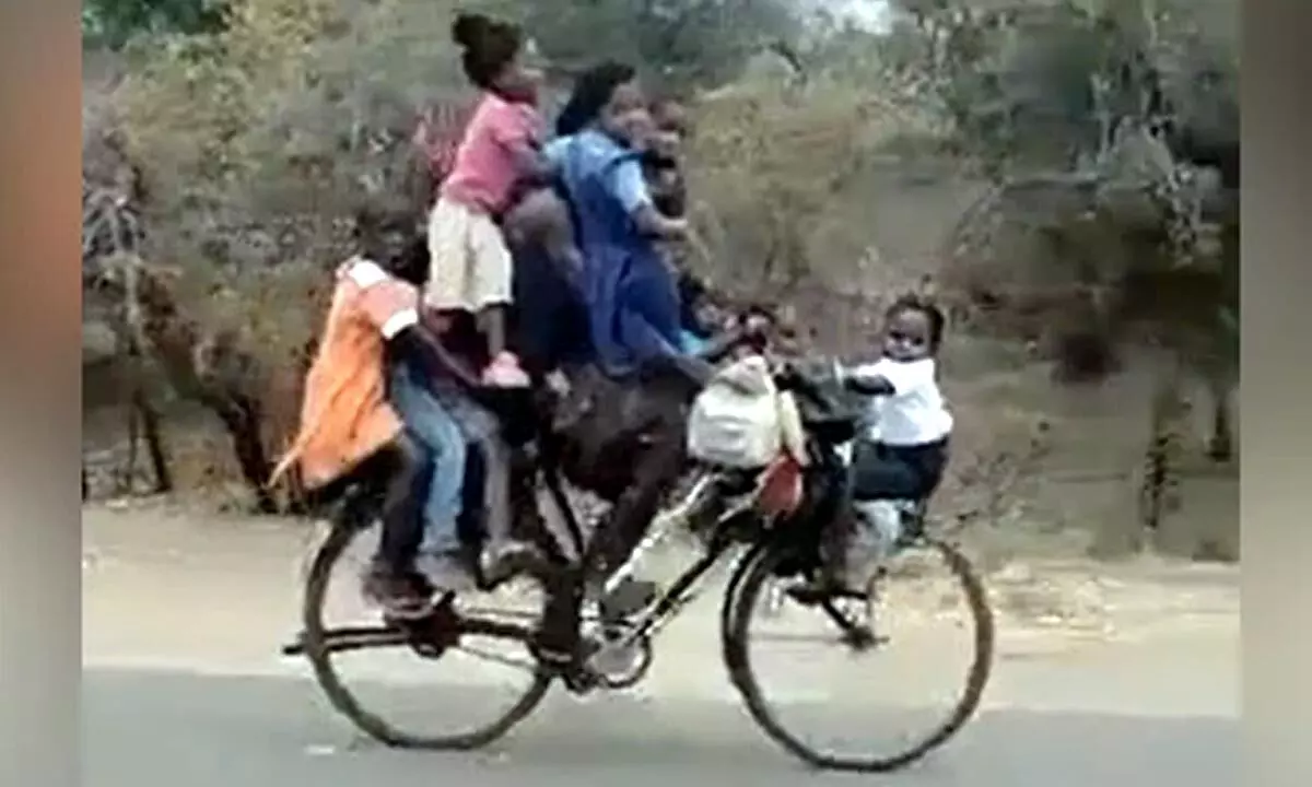 Social media users are sharing a trending video of a father riding a bicycle while pulling nine kids.