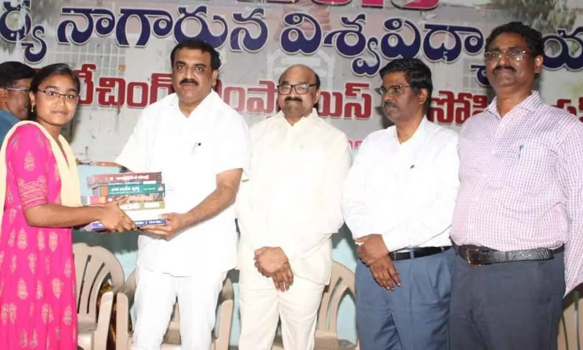Special Commissioner of Agriculture Cherukuri Harichandan giving free study material to a merit student at a programme in Guntur on Thursday