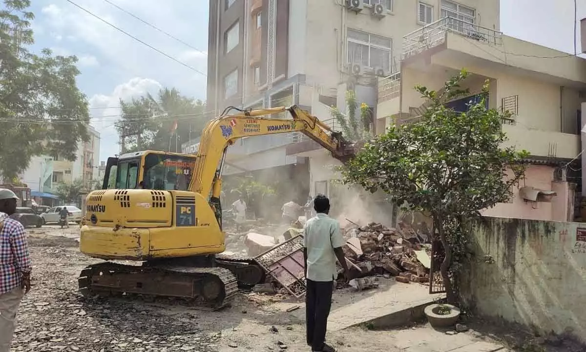 GMC staff demolishing compound wall of a house to take Donka Road widening work in Guntur city